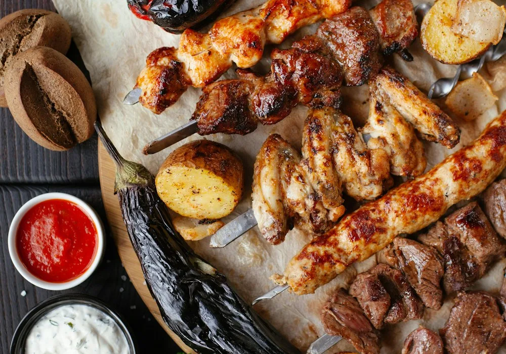 Grilled skewers, vegetables, and potatoes served on a sharing platter